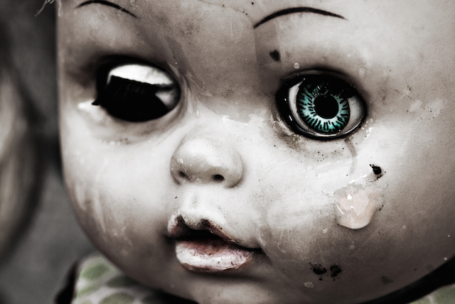 Concept: Abandoned Person. Close up of an old doll`s face with tear. Spesial grunge-fashioned image with grain