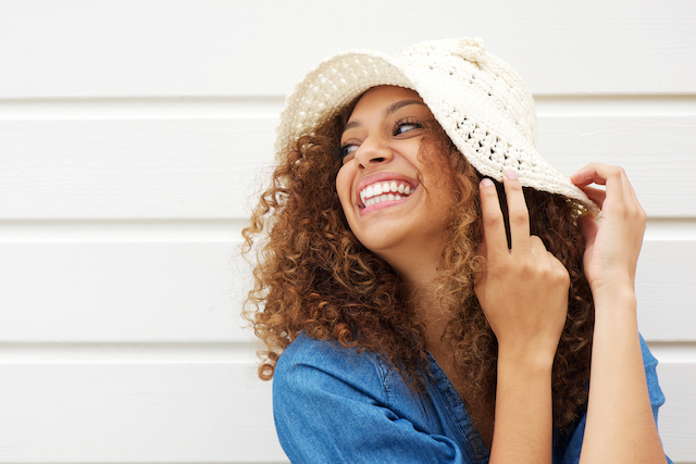 Portrait of a beautiful young woman laughing and wearing summer hat